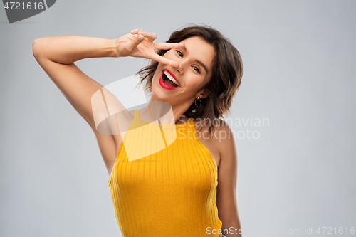 Image of happy smiling young woman showing peace hand sign