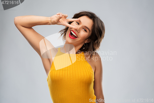 Image of happy smiling young woman showing peace hand sign