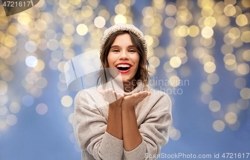 Image of woman in winter hat sending air kiss on christmas