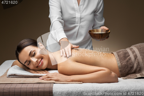 Image of beautiful young woman having salt massage at spa