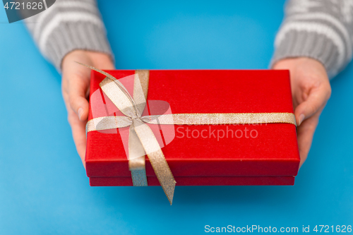 Image of hands holding red christmas gift box