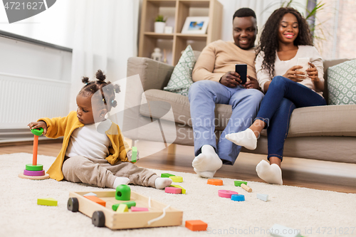 Image of african baby girl playing with toy blocks at home