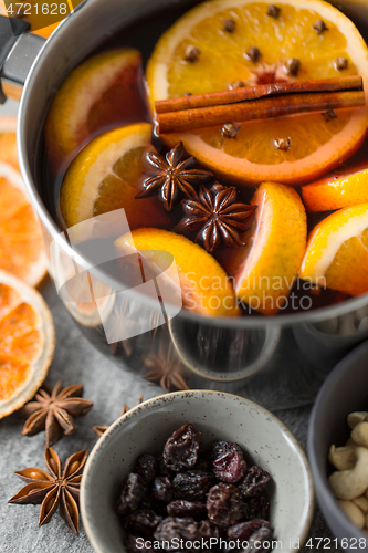 Image of pot with hot mulled wine, orange slices and spices