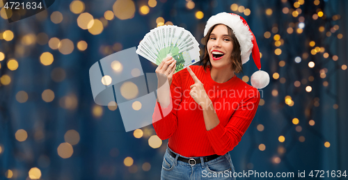 Image of happy woman in santa hat with money on christmas