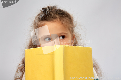 Image of little girl hiding behind yellow book
