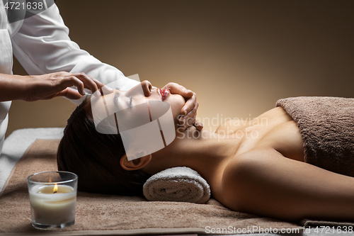 Image of woman having face and head massage at spa