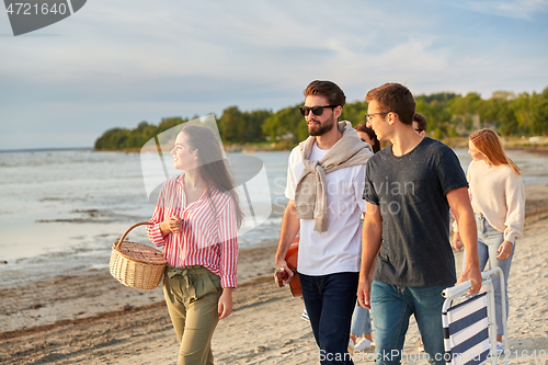 Image of happy friends walking along summer beach