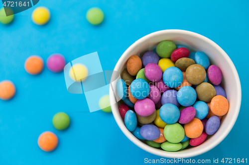 Image of candy drops in paper cup on blue background