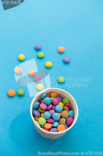 Image of candy drops in paper cup on blue background