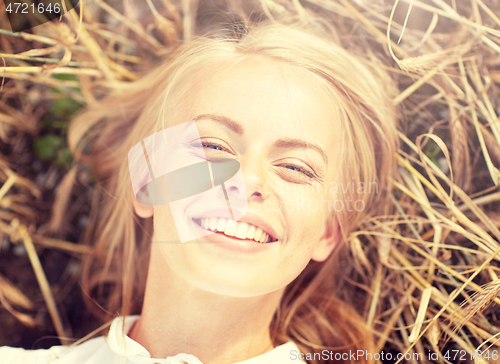 Image of happy young woman lying on cereal field