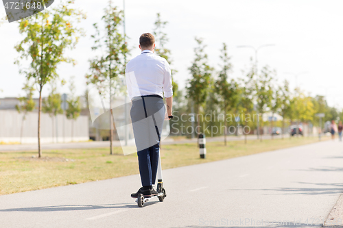 Image of young businessman riding electric scooter outdoors