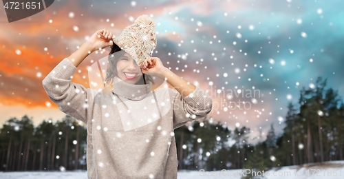 Image of woman in hat and sweater over winter forest