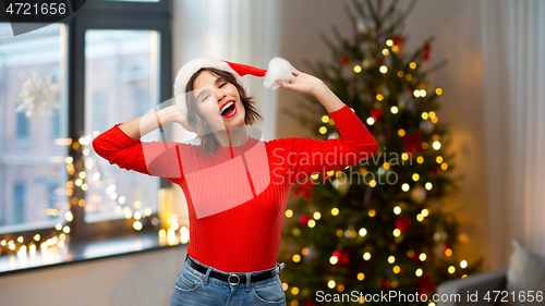 Image of happy young woman in santa hat on christmas