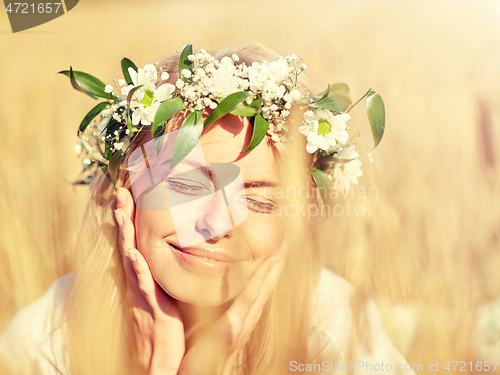 Image of happy woman in wreath of flowers on cereal field