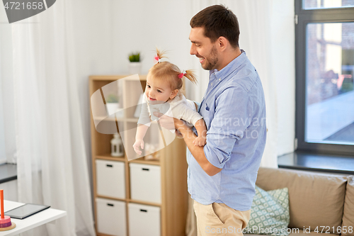 Image of happy father playing with baby daughter at home