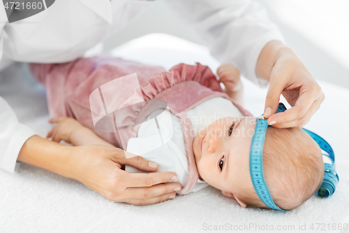 Image of pediatrician doctor measuring bab\'s head at clinic