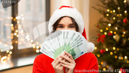 Image of happy woman in santa hat with money on christmas