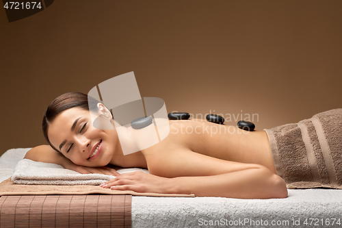 Image of smiling woman having hot stone massage at spa