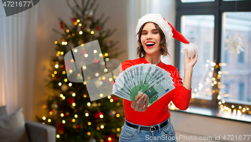 Image of happy woman in santa hat with money on christmas