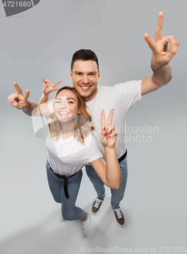 Image of happy couple in white t-shirts showing peace