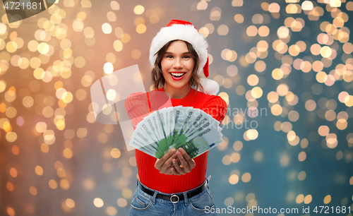 Image of happy woman in santa hat with money on christmas