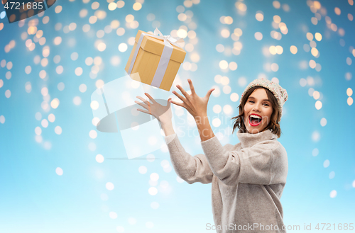 Image of young woman in winter hat catching gift box