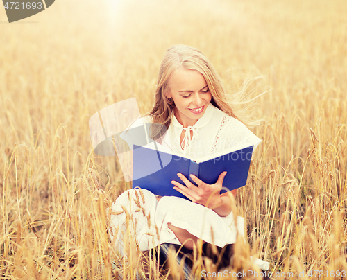 Image of smiling young woman reading book on cereal field