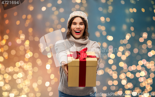 Image of young woman in knitted winter hat holding gift box