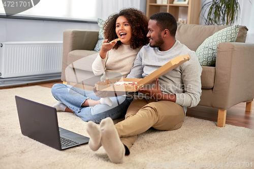 Image of happy african american couple eating pizza at home