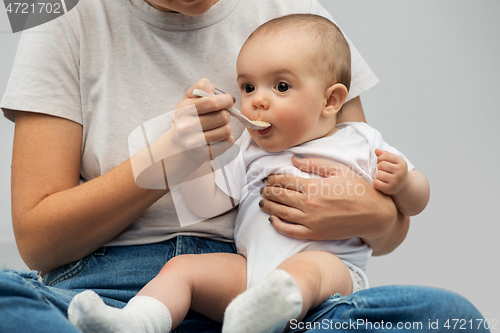 Image of close up of mother with spoon feeding little baby