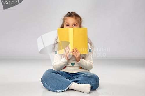 Image of little girl with book sitting on floor