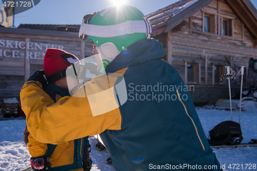 Image of father preparing his little son for the first time on a snowboar