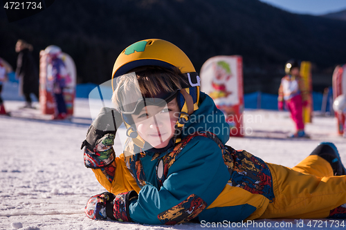 Image of little snowboarder lying on the snow