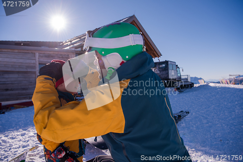 Image of father preparing his little son for the first time on a snowboar