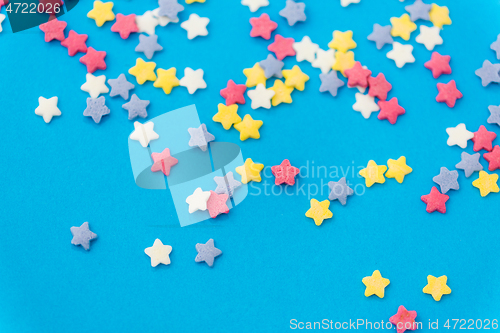 Image of star shaped pastry sprinkles on blue background