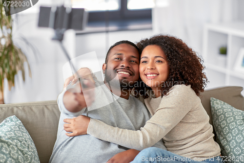 Image of couple taking picture by selfie stick at home