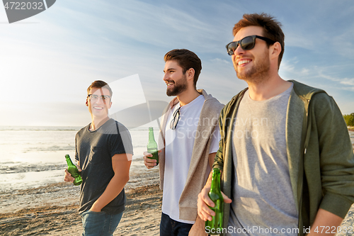 Image of young men with non alcoholic beer walking on beach