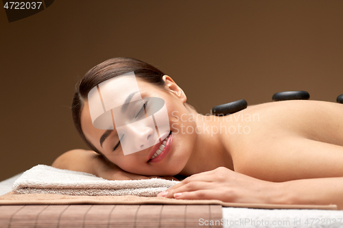 Image of smiling woman having hot stone massage at spa