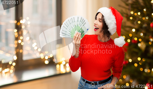 Image of happy woman in santa hat with money on christmas