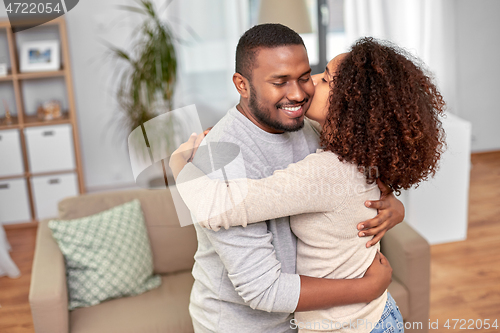 Image of happy african american couple kissing at home