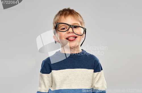 Image of portrait of little boy in glasses showing tongue