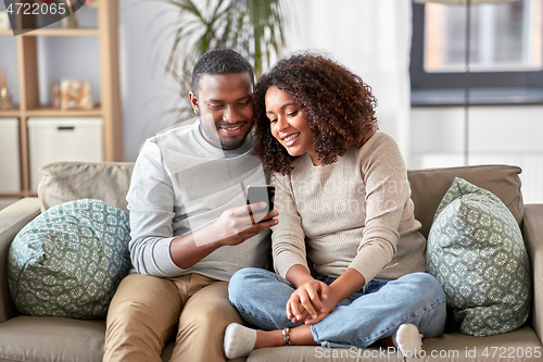 Image of african american couple with smartphone at home