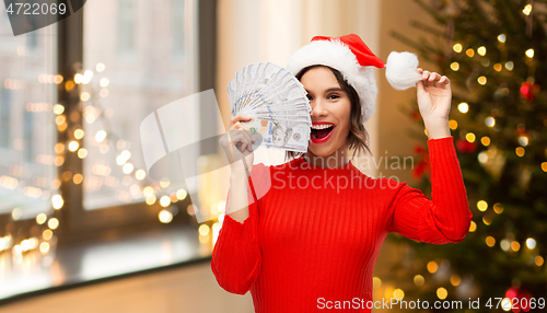 Image of happy woman in santa hat with money on christmas