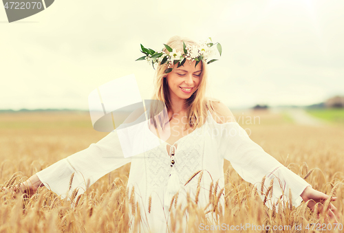 Image of happy young woman in flower wreath on cereal field