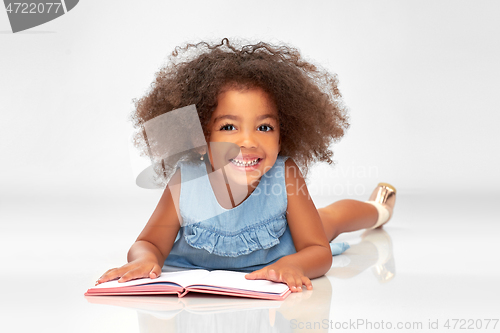 Image of smiling little african american girl reading book