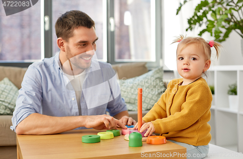 Image of father playing with little baby daughter at home