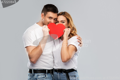 Image of smiling couple hiding behind big red heart