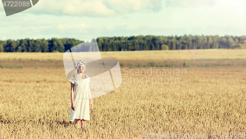 Image of happy young woman in flower wreath on cereal field