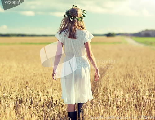 Image of happy young woman in flower wreath on cereal field