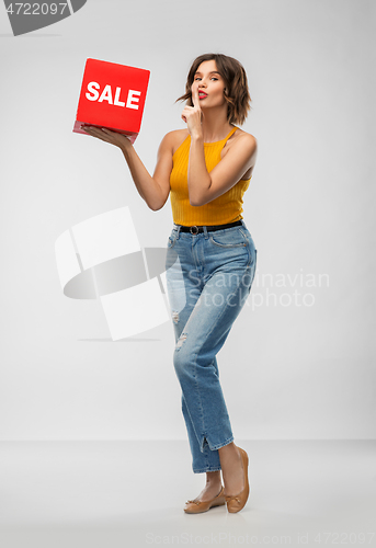 Image of happy smiling young woman posing with sale sign